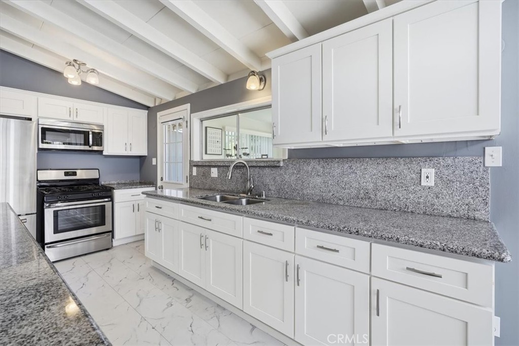 533 South Devon Road Orange, CA 92868 - Photo 35 of 50 a kitchen with granite countertop white cabinets and stainless steel appliances