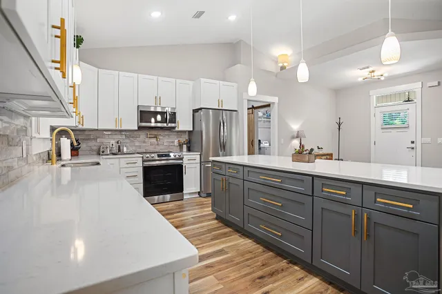 a kitchen with kitchen island granite countertop a sink cabinets and stainless steel appliances
