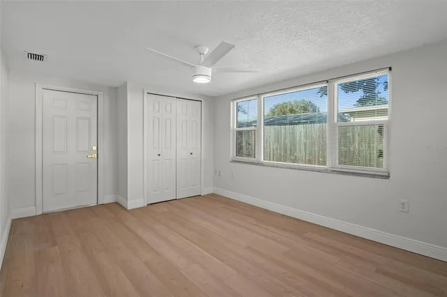 a view of empty room with wooden floor and fan