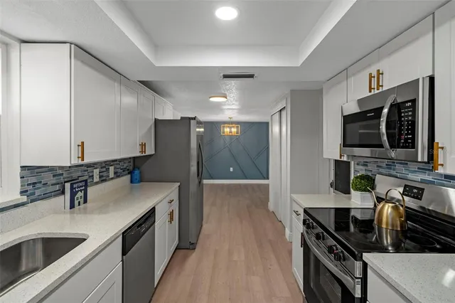 a kitchen with stainless steel appliances granite countertop a sink and a stove top oven with wooden floor
