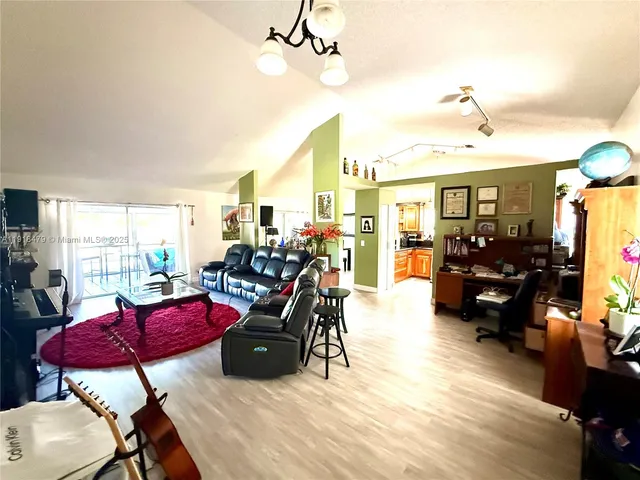 a living room with furniture kitchen view and a chandelier