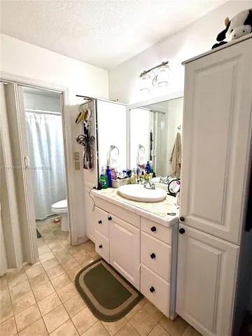 a bathroom with a sink a toilet and shower a mirror