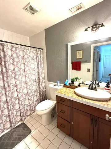 a bathroom with a double vanity sink toilet mirror and shower