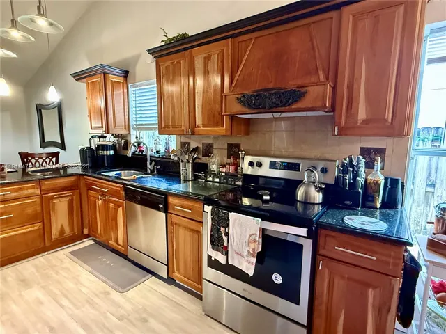 a kitchen with stainless steel appliances granite countertop a sink stove and cabinets
