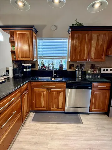 a kitchen with granite countertop wooden cabinets a stove top oven and granite counter tops