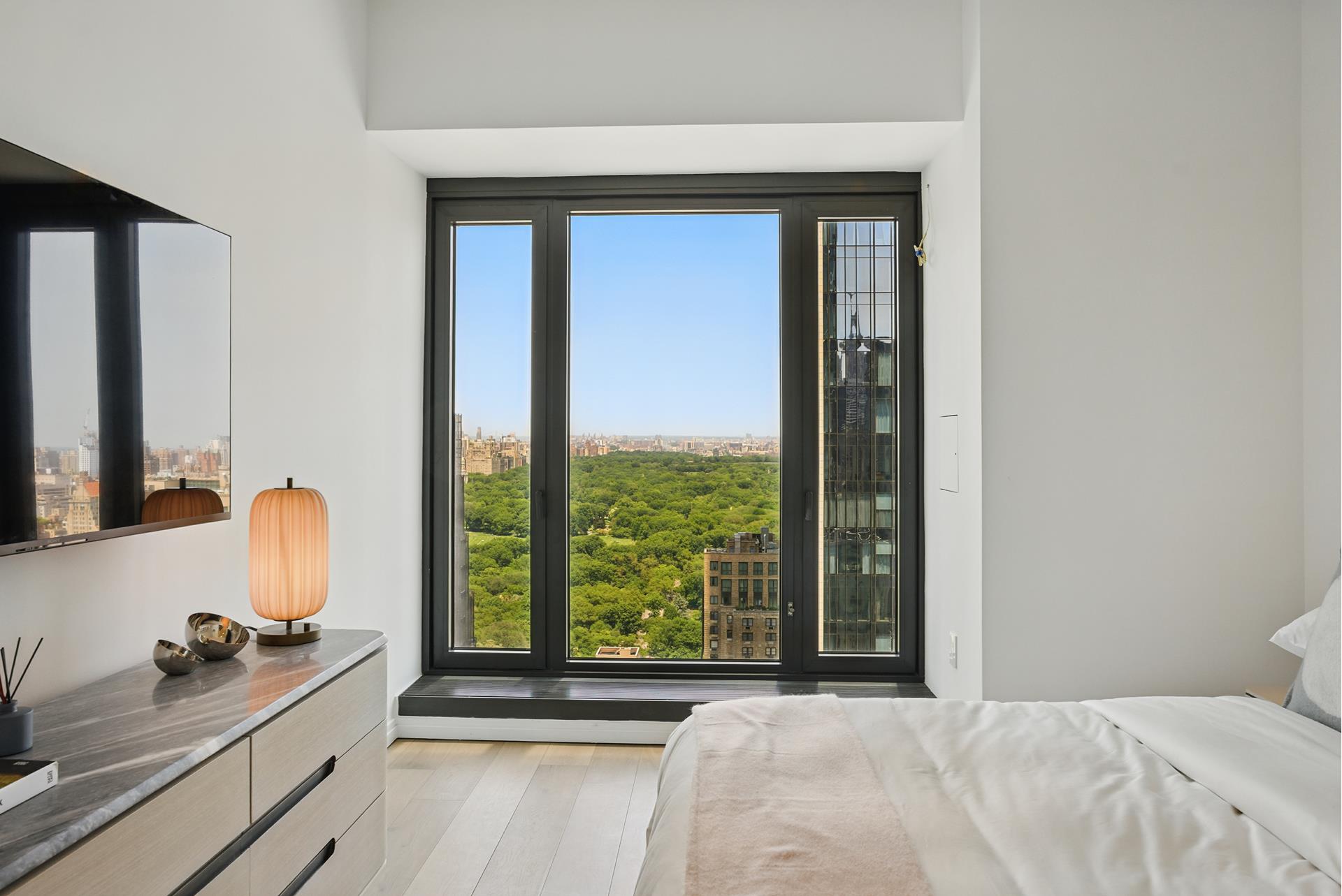 111 West 56th Street, Unit 41K Manhattan, NY 10019 - Photo 4 of 13 a bedroom with a bed and large windows