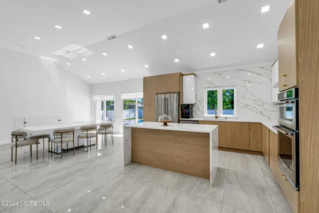 a kitchen with stainless steel appliances kitchen island granite countertop a table chairs and a refrigerator