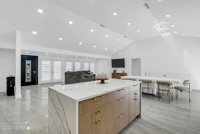 a kitchen with a stove a sink a kitchen island with chairs and wooden floor