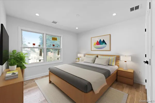 a spacious bedroom with a large bed a potted plant and a window