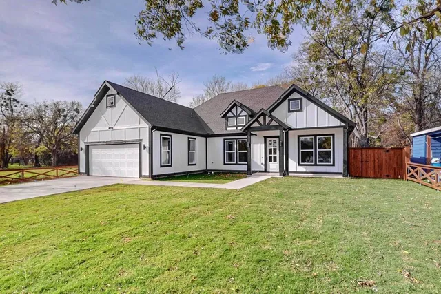 a front view of a house with a garden and trees