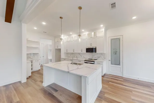 a large kitchen with kitchen island a sink stainless steel appliances and cabinets
