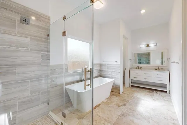 a bathroom with a white tub a mirror and a shower