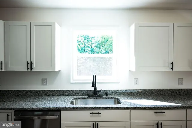 a kitchen with granite countertop white cabinets and a stove