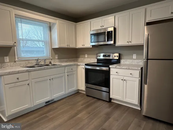 a kitchen with white cabinets white stainless steel appliances and sink