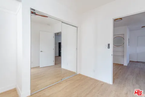 a view of a hallway with wooden floor and a bathroom