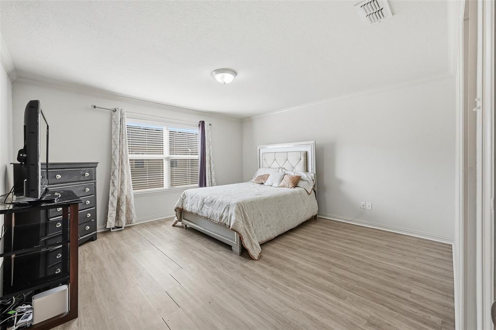 6913 Sandshell Boulevard Fort Worth, TX 76137 - Photo 3 of 24 a bedroom with a bed flat screen tv and a window