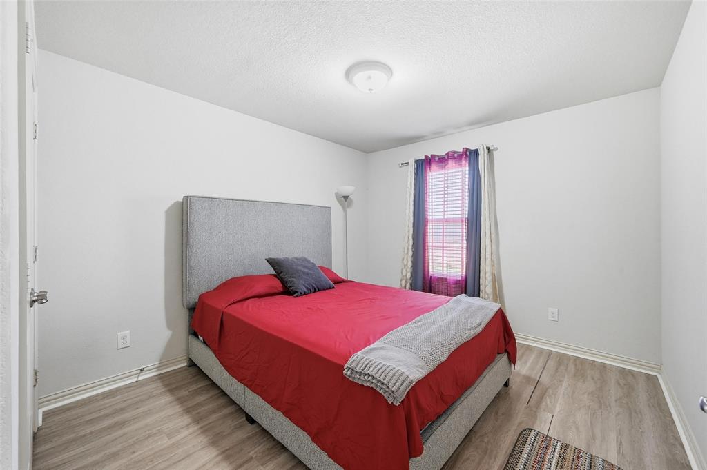 6913 Sandshell Boulevard Fort Worth, TX 76137 - Photo 9 of 24 a bedroom with a bed and wooden floor