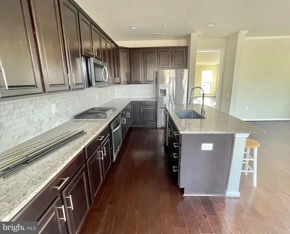 a kitchen with stainless steel appliances granite countertop refrigerator a sink and wooden cabinets