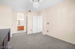 7701 West Robindale Road, Unit 277 Las Vegas, NV 89113 - Photo 14 of 33 A well-lit bedroom features plush carpeting and a view into an adjoining bathroom.