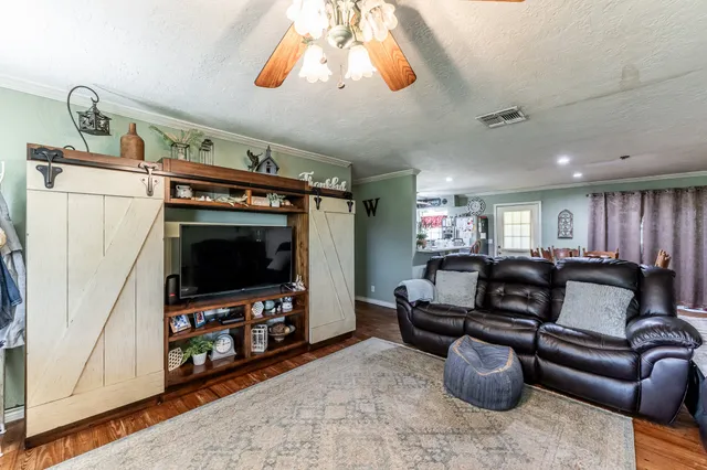 a living room with furniture a flat screen tv and a refrigerator