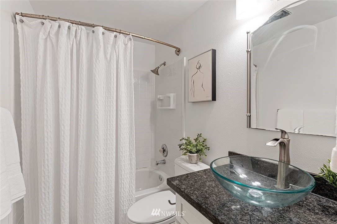 5909 Southwest Carroll Street, Unit 101 Seattle, WA 98116 - Photo 11 of 12 a bathroom with a granite countertop sink and a mirror