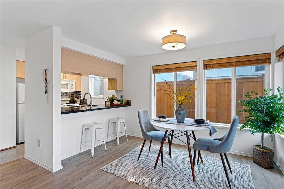 5909 Southwest Carroll Street, Unit 101 Seattle, WA 98116 - Photo 5 of 12 a dining room with furniture a potted plant and wooden floor