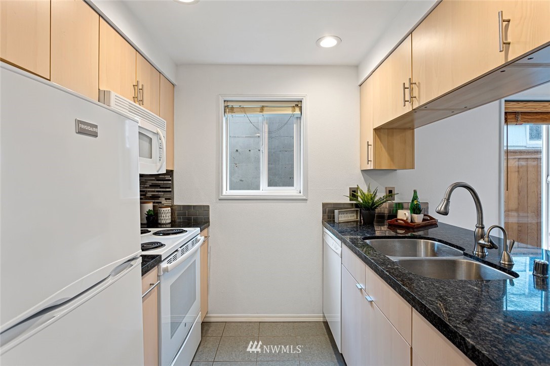 5909 Southwest Carroll Street, Unit 101 Seattle, WA 98116 - Photo 6 of 12 a kitchen with stainless steel appliances granite countertop a sink stove and refrigerator