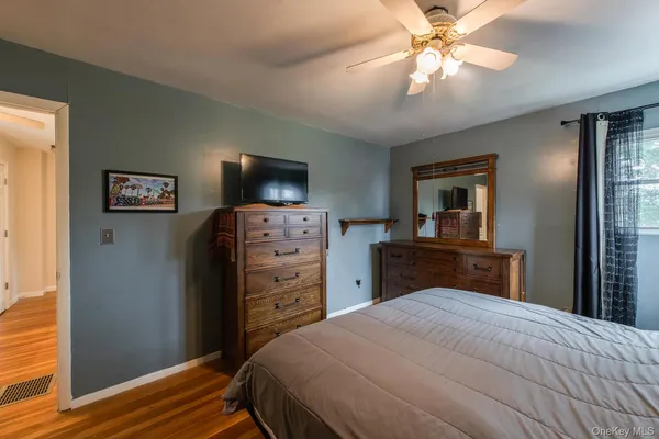 a bedroom with a bed and a flat tv screen on dresser