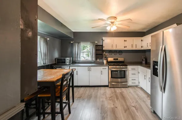 a kitchen with a refrigerator a sink dishwasher a stove and a dining table with wooden floor