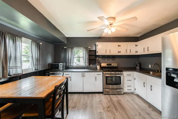 a kitchen with stainless steel appliances granite countertop a stove a sink dishwasher a microwave oven with a dining table and chairs with wooden floor