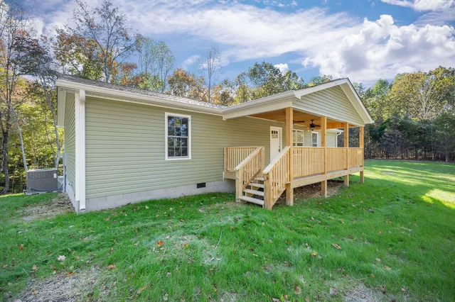 a view of a small house with a small yard and a wooden deck