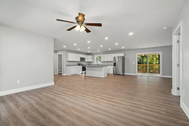 a view of an empty room with a window and wooden floor