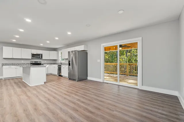 a view of kitchen with stainless steel appliances kitchen island wooden floor and window
