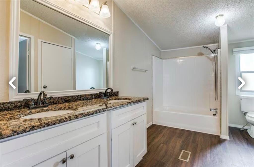 168 Prairie Lane Azle, TX 76020 - Photo 11 of 16 Full bathroom with double vanity, a textured ceiling, shower / tub combination, dark wood finished floors, and crown molding