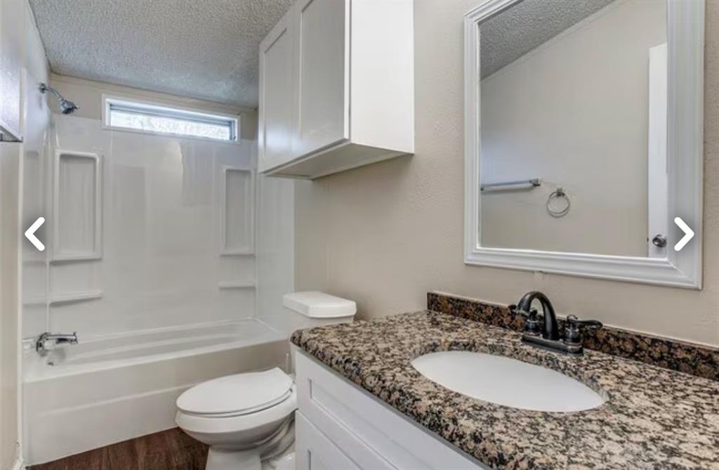 168 Prairie Lane Azle, TX 76020 - Photo 13 of 16 Full bathroom featuring a textured ceiling, vanity, washtub / shower combination, and dark wood-type flooring