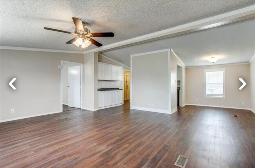 168 Prairie Lane Azle, TX 76020 - Photo 5 of 16 Unfurnished living room featuring ornamental molding, lofted ceiling, a ceiling fan, a textured ceiling, and dark wood-type flooring