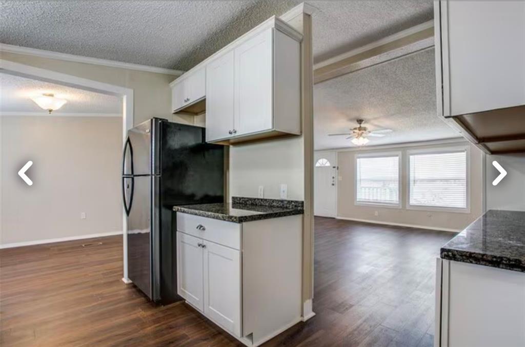 168 Prairie Lane Azle, TX 76020 - Photo 16 of 16 Kitchen featuring a textured ceiling, dark wood-style floors, open floor plan, white cabinets, and crown molding