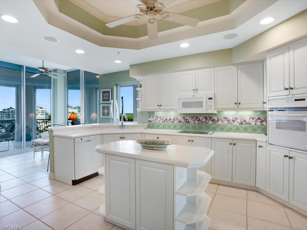 425 Dockside Drive, Unit PH1 Naples, FL 34110 - Photo 17 of 34 a kitchen with kitchen island granite countertop white cabinets white appliances with a sink and dishwasher
