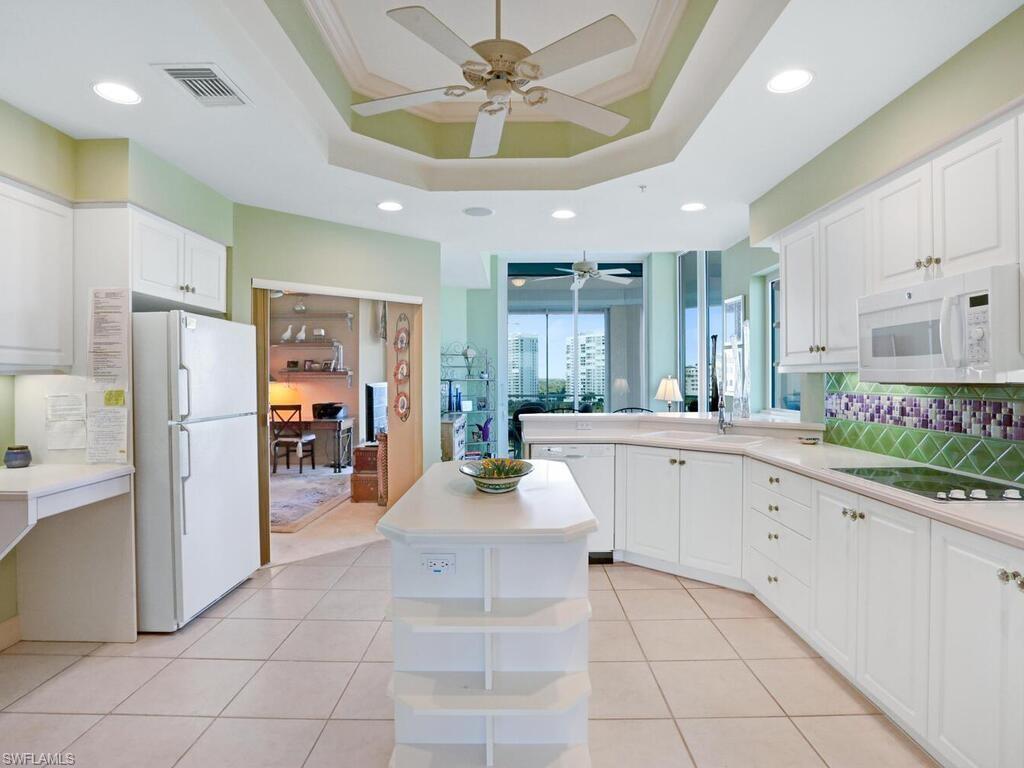 425 Dockside Drive, Unit PH1 Naples, FL 34110 - Photo 20 of 34 a large white kitchen with a refrigerator a stove a sink a dining table and chairs