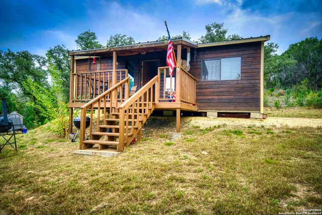 a view of wooden house with a small yard and wooden fence
