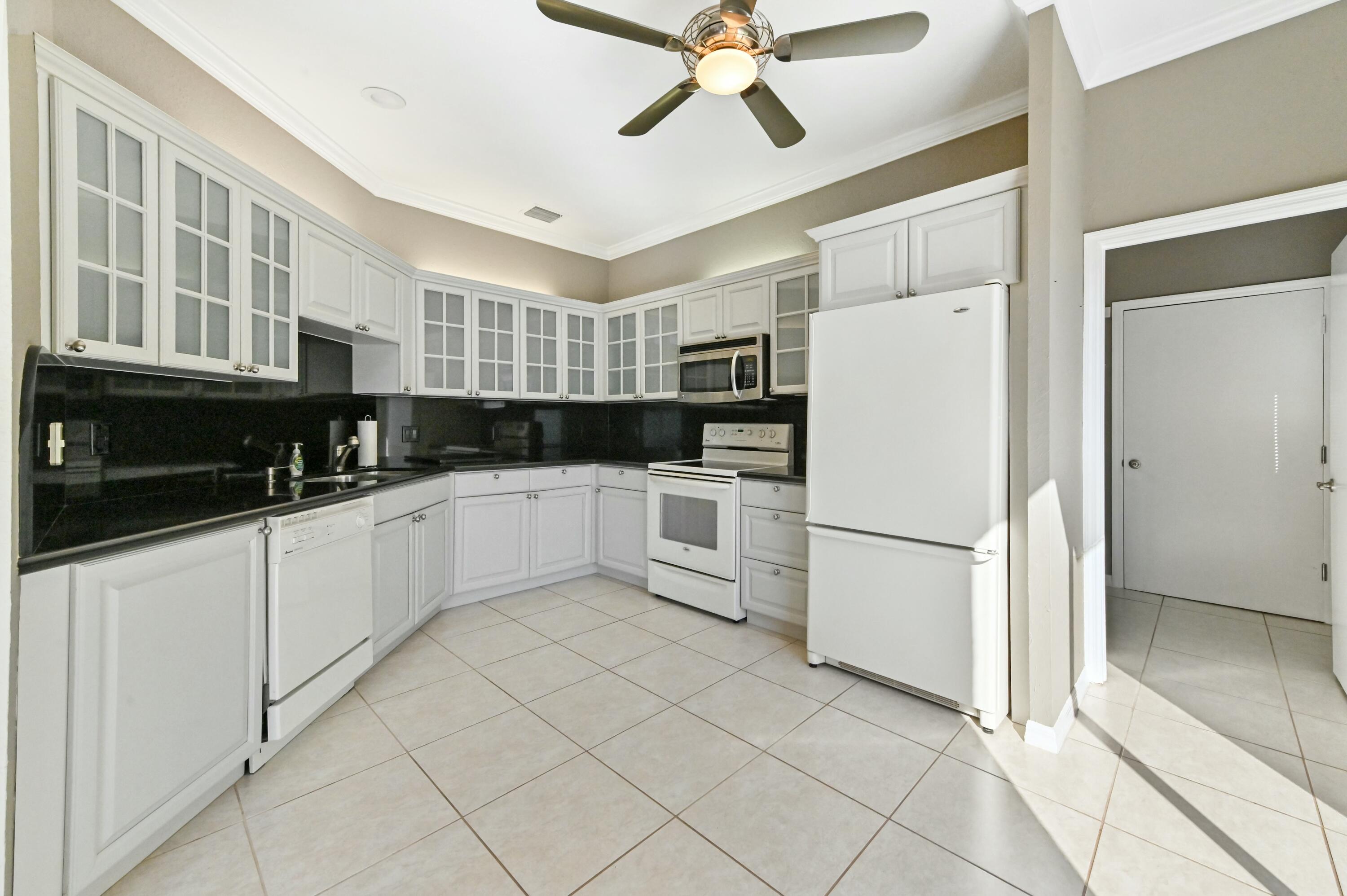 17272 Hampton Boulevard Boca Raton, FL 33496 - Photo 15 of 33 a kitchen with white cabinets and white appliances