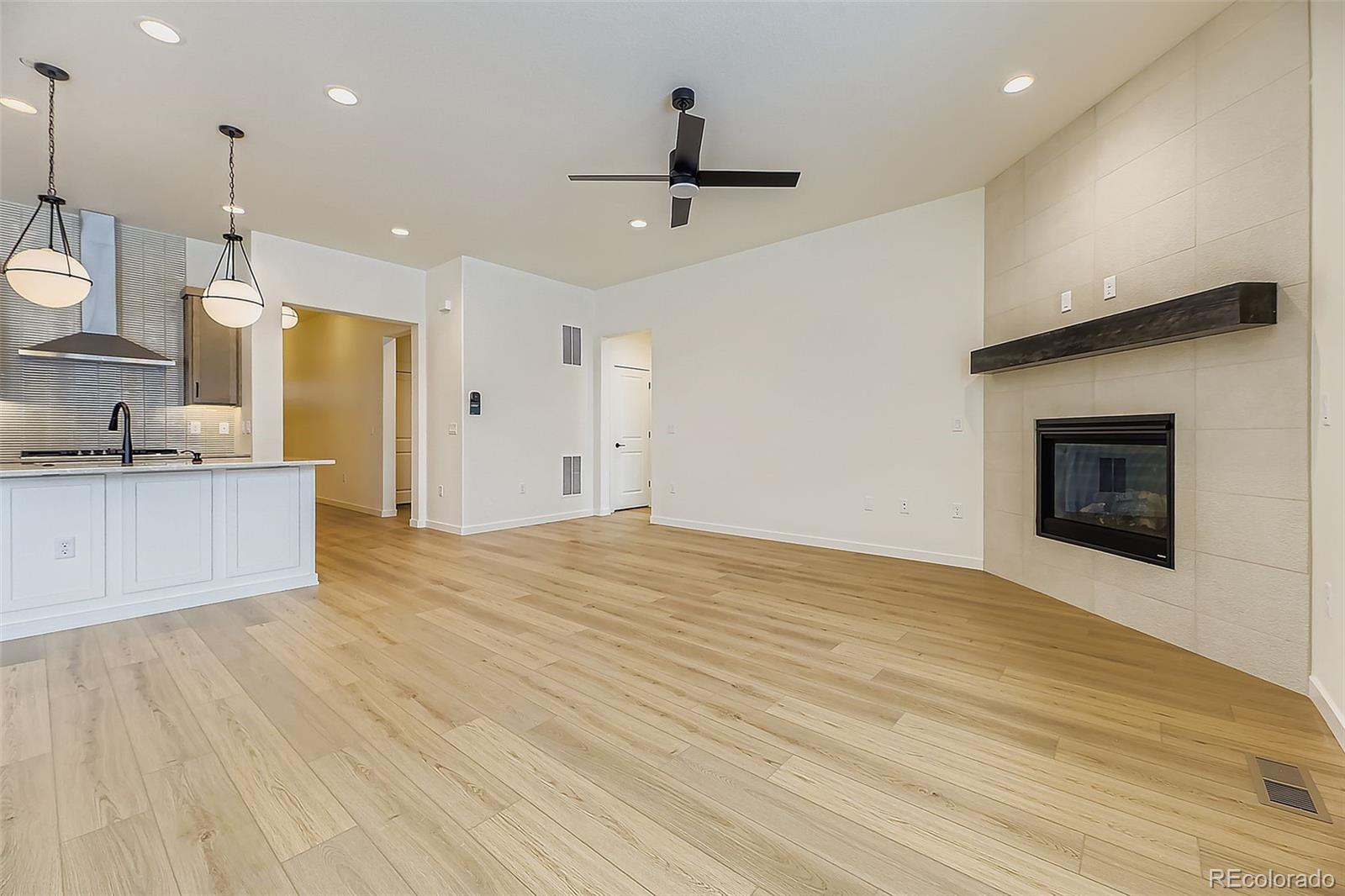 8942 South Riviera Way Aurora, CO 80016 - Photo 8 of 29 a view of an empty room and kitchen with fireplace wooden floor