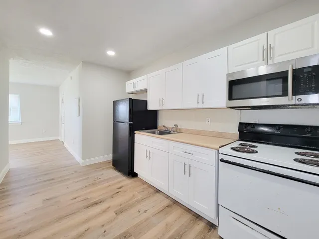 a kitchen with granite countertop white cabinets and stainless steel appliances