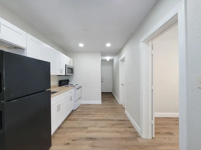 a large white kitchen with a stove a refrigerator and a sink