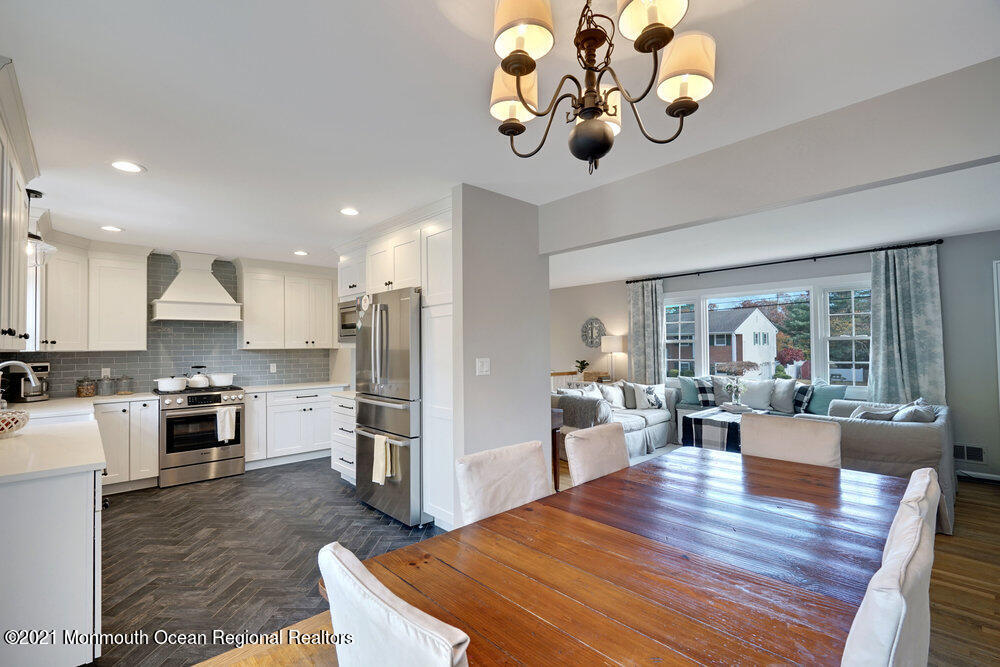 557 Summit Drive Point Pleasant, NJ 08742 - Photo 9 of 41 a view of a dining room and livingroom with furniture wooden floor a rug a flat screen tv a rug a fireplace and a large window