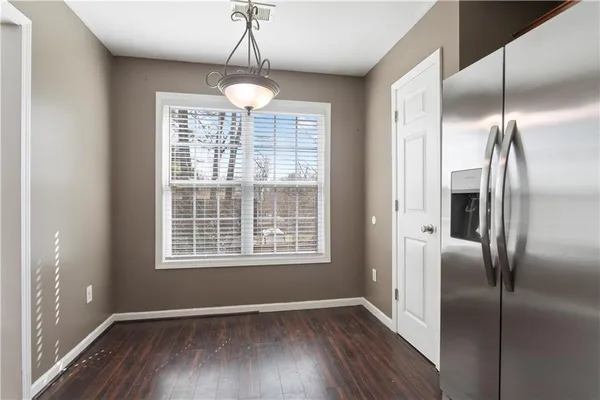 a view of an empty room with wooden floor fridge and a window