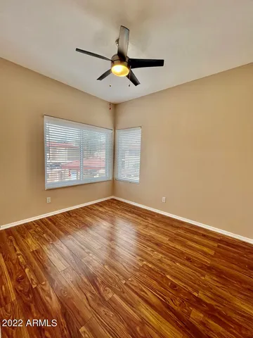 an empty room with wooden floor chandelier fan and windows