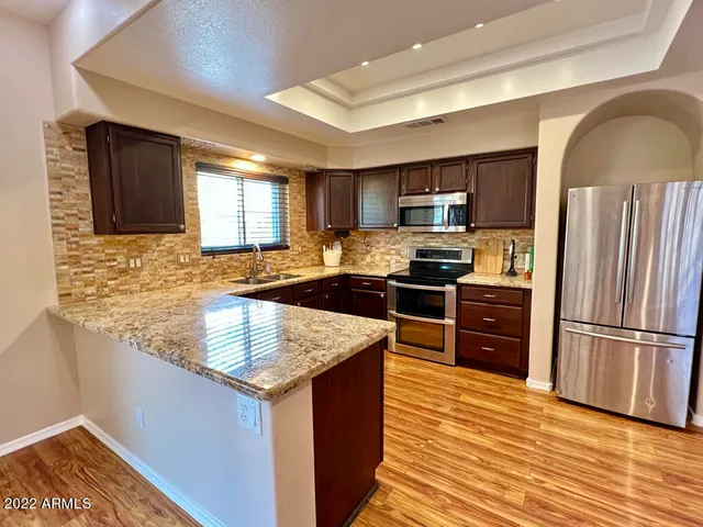 a kitchen with granite countertop a refrigerator stove top oven and sink