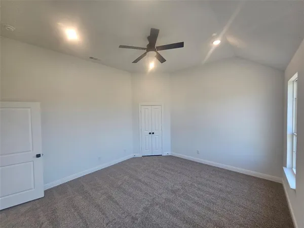 an empty room with windows and chandelier fan
