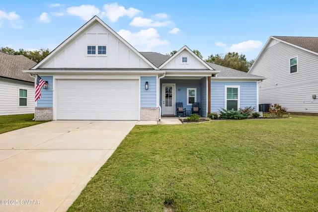 a view of a white house next to a yard and palm tree
